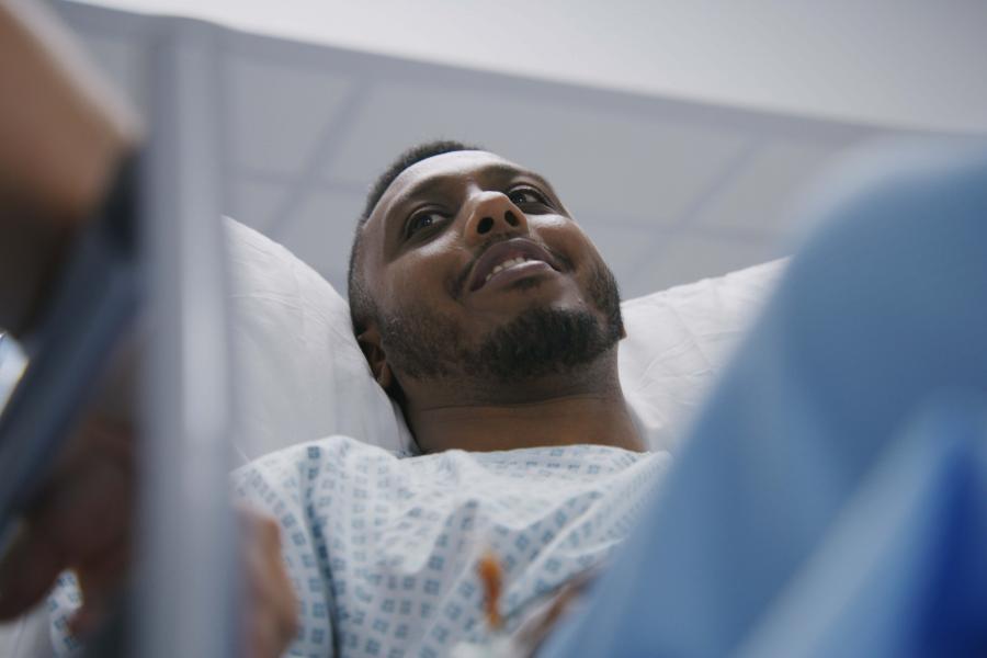 A man lies on stretcher and talks with doctors before operation.