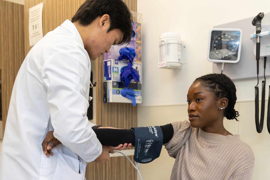 A medical student puts on a blood pressure cuff on a patient.