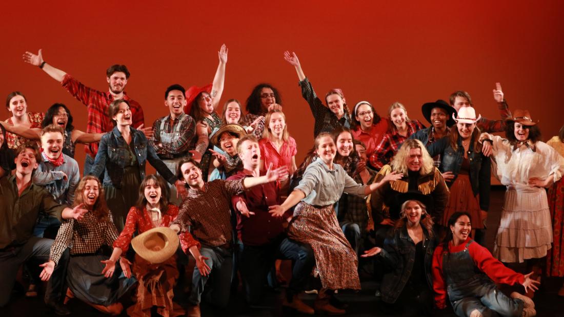 Performers dressed as cowboys pose with arms extended at the end of their performance of The Farmer and the Cowman, from the musical Oklahoma