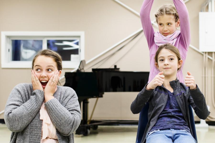 A group of three musical theatre participants sing and act together.