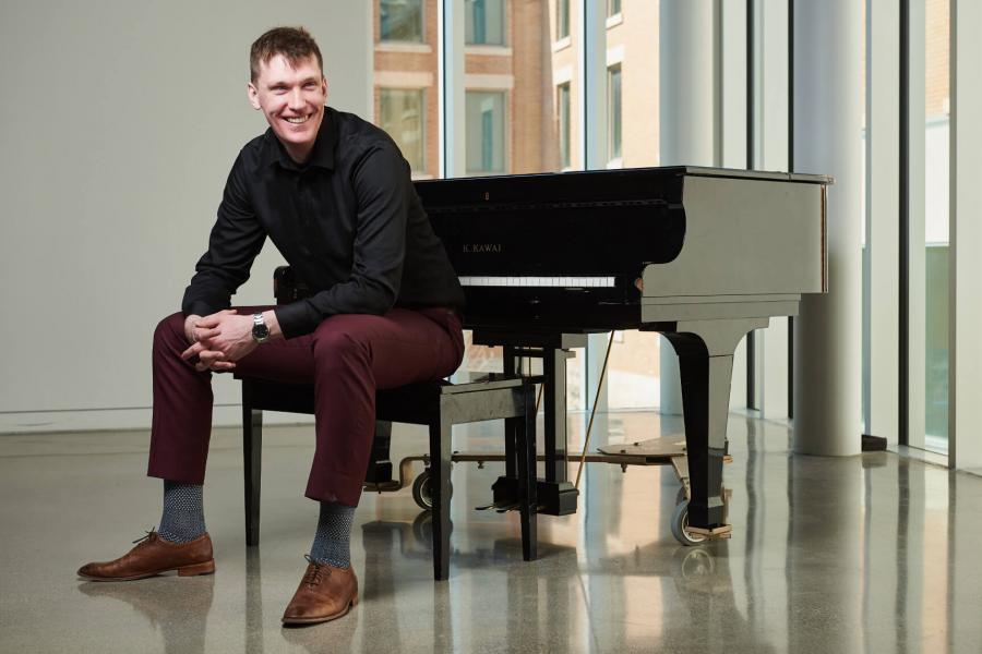 A faculty of music student sits at a piano.