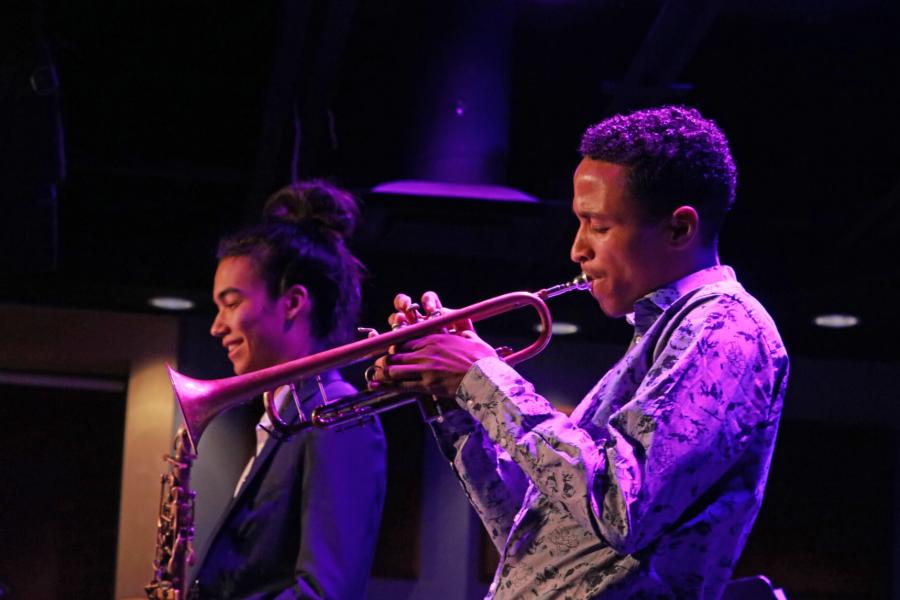 Two students from the Desautels Faculty of Music perform together on stage, both are washed in a purple spotlight. 