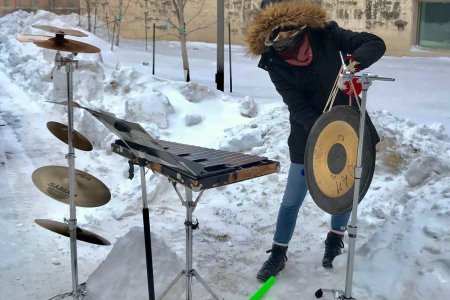 A study in winter gear performs a midday concert outside in the middle of winter.