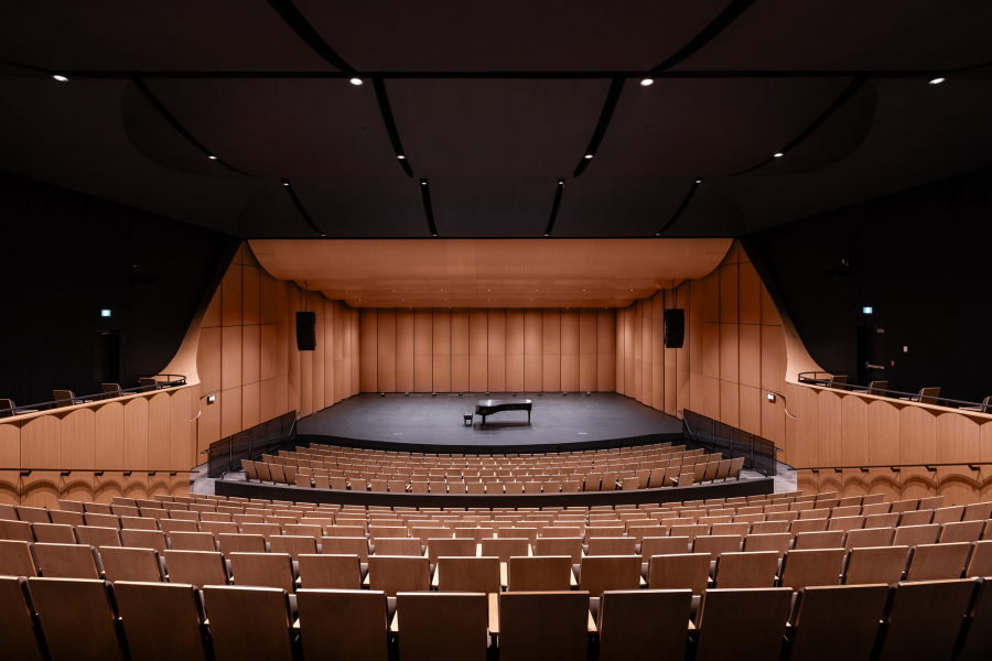 interior image of the Desautels concert hall. The hall is empty, with a piano in the centre of the stage.