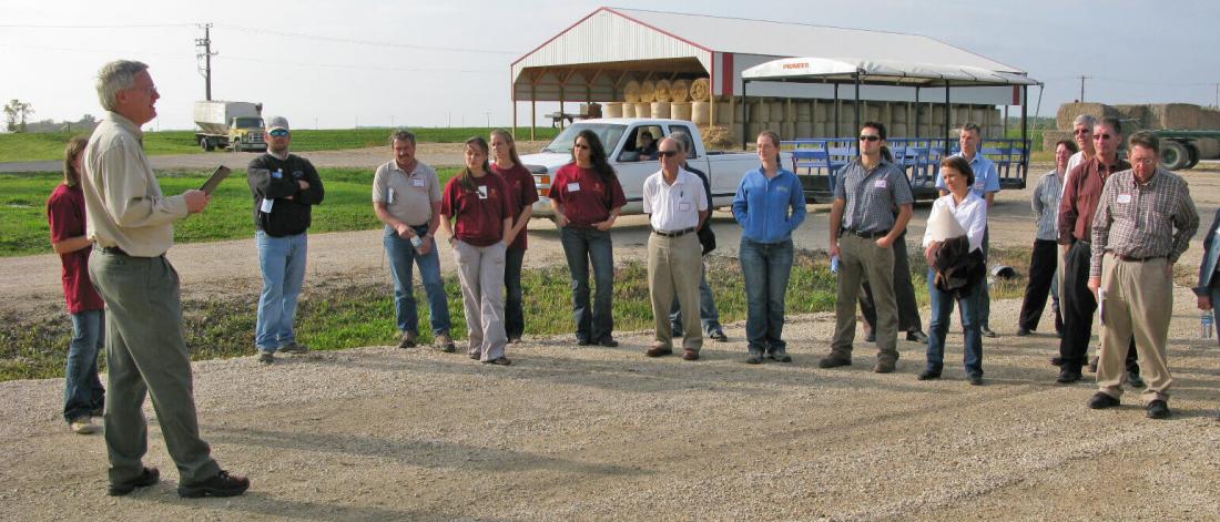 People listening to discussion near farm