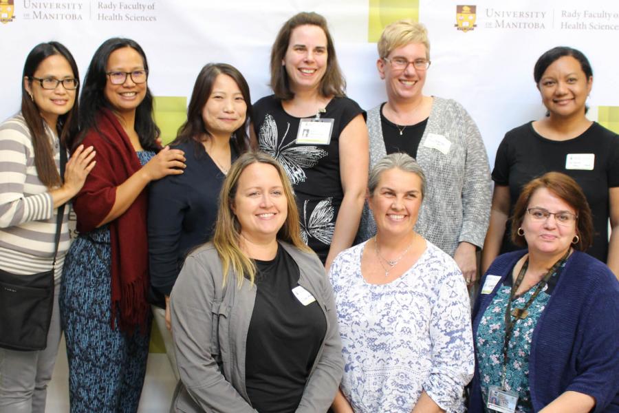 A group of nine Nursing Alumna gather together for a group photo at a class reunion. 