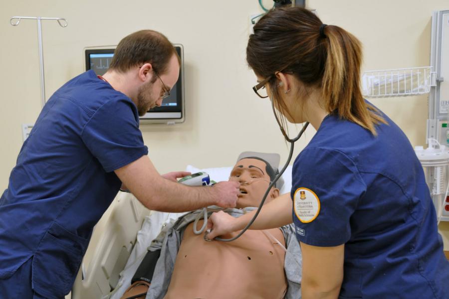 Two nursing students work in a robotic patient in the Sim Lab.