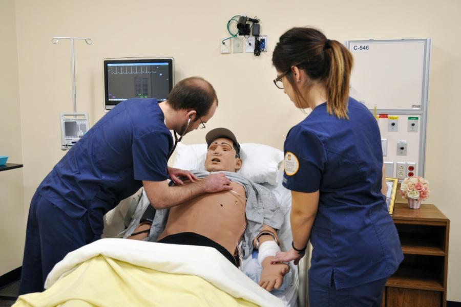 Two nursing students working on a sim patient.