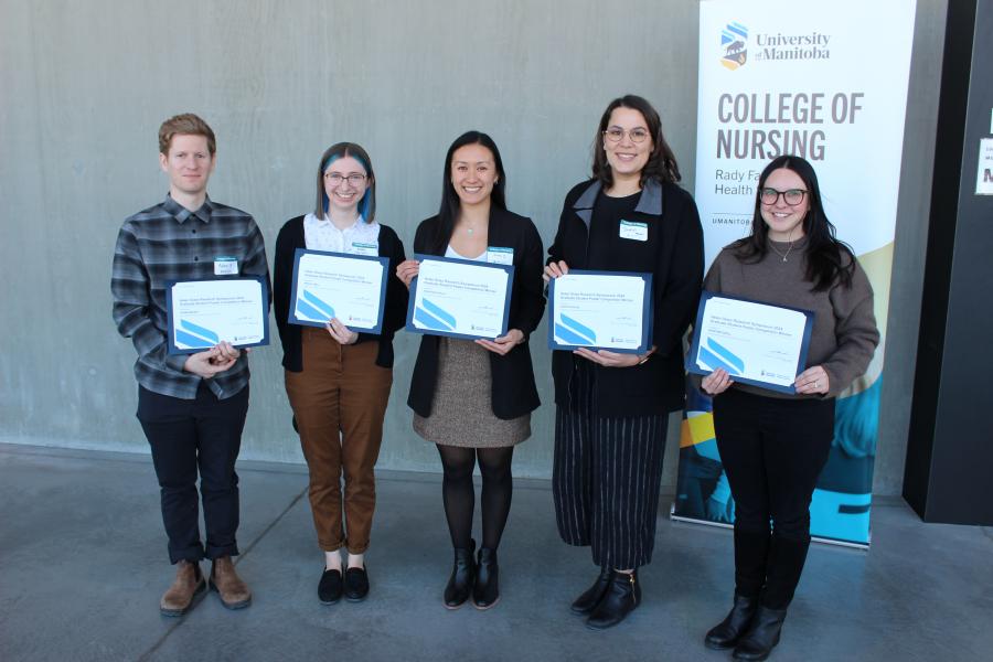 Five students stand holding award certificates in front of a University of Manitoba College of Nursing banner.