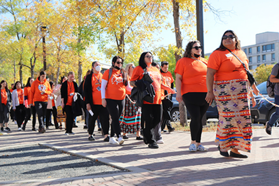 A group of orange-clad students, faculty and staff participating in the annual Orange Shirt Day walk.