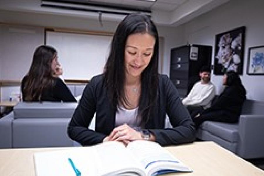 Student sitting at a desk with a book.