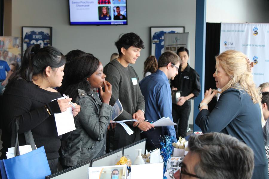 Students discuss career options with a professional at a career fair booth.