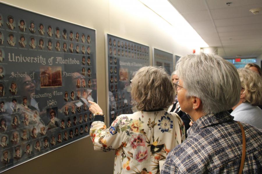 A nursing alumna spots their framed graduation photo that is mounted in the Helen Glass Centre for Nursing.