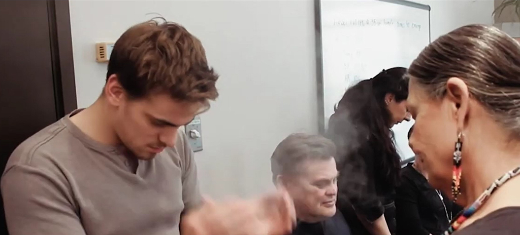 A person cleanses themselves during a smudge ceremony.