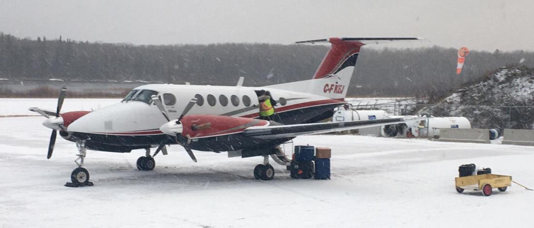 A small plane being loaded on a snowy runway.