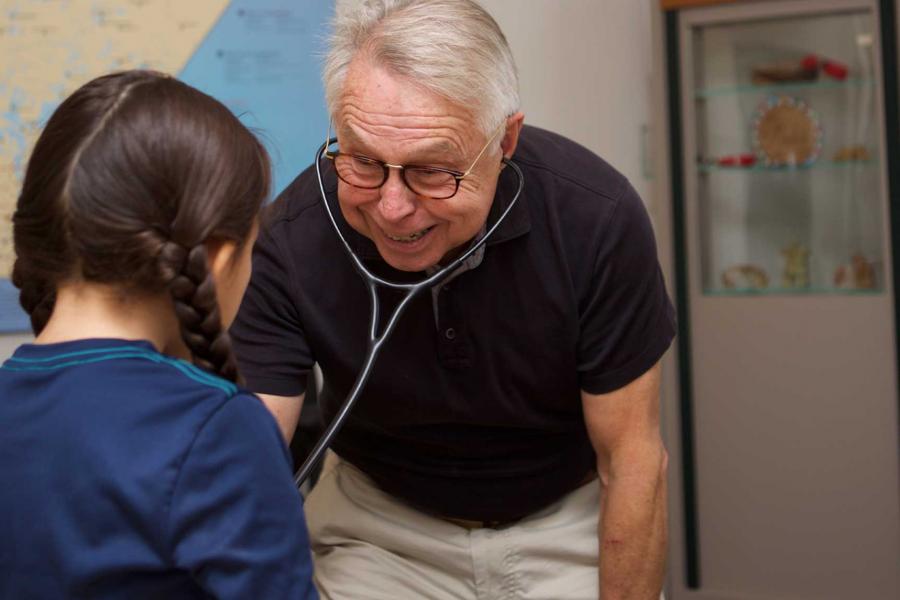 a doctor smiles at a young Indigenous boy.