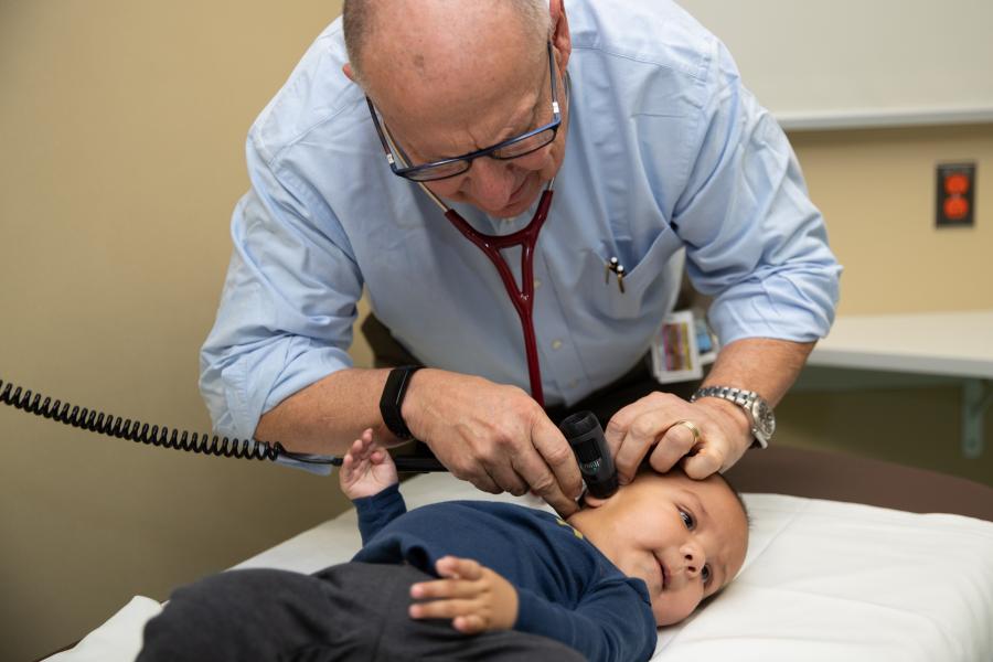 Pediatrician checks the hearing of a small child lying on a medical table.