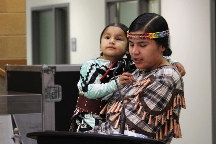 Woman in traditional Indigenous dress holding a child.