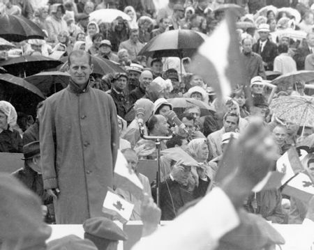 Prince Philip stands in rain at opening of 67 Games at Winnipeg Stadium