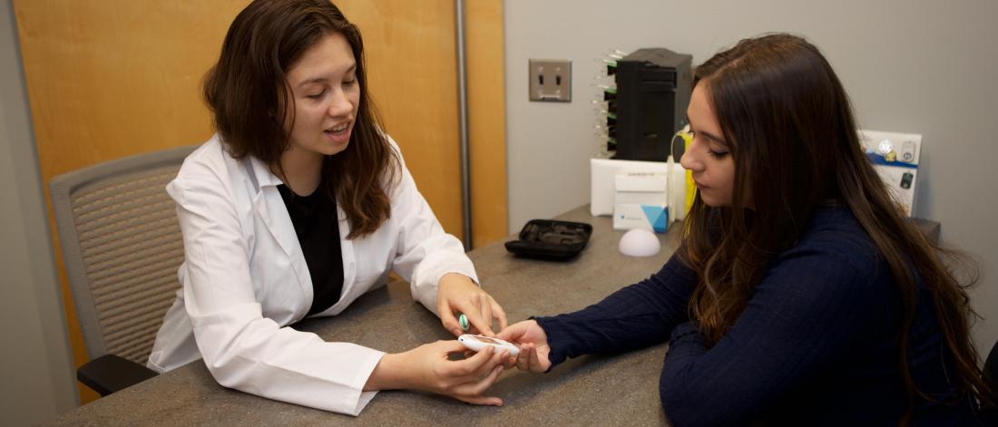 A pharmacist reviews medication with a student pharmacist.