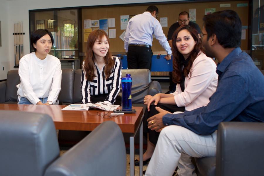 Students of the College of Pharmacy gather together in a student lounge area talking.