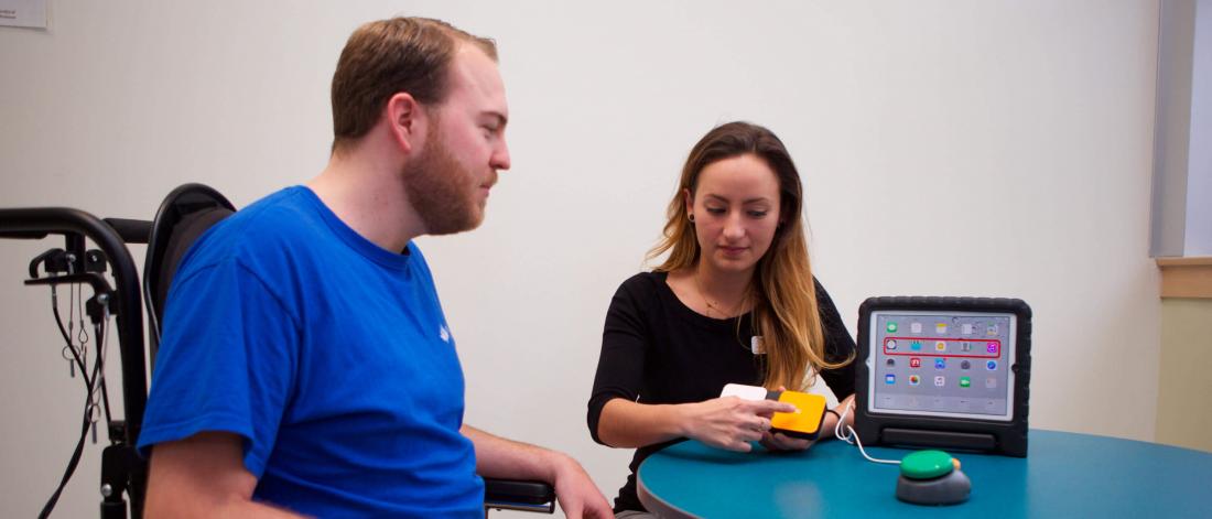 An occupational therapist sits at a desk with a client.