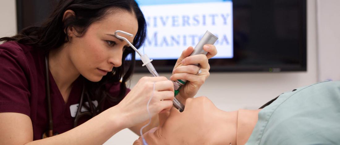 A respiratory therapy student works with a mannequin.