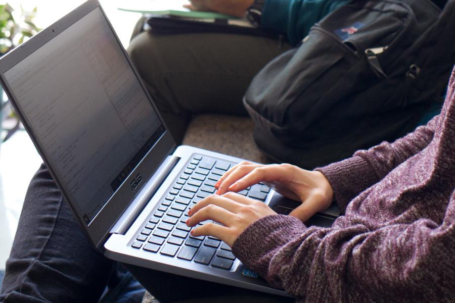 Hands typing on a laptop keyboard.