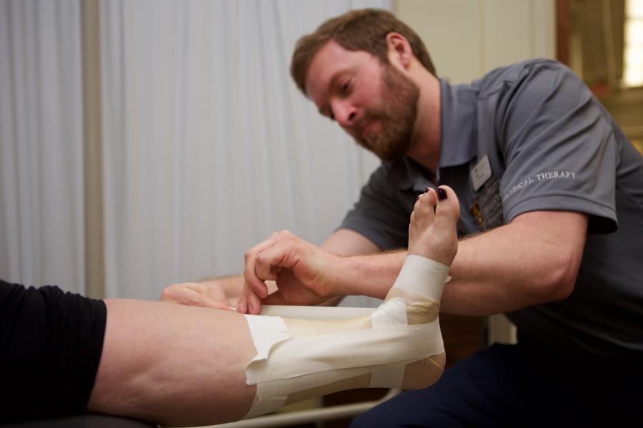 Physical therapist bandaging an ankle.