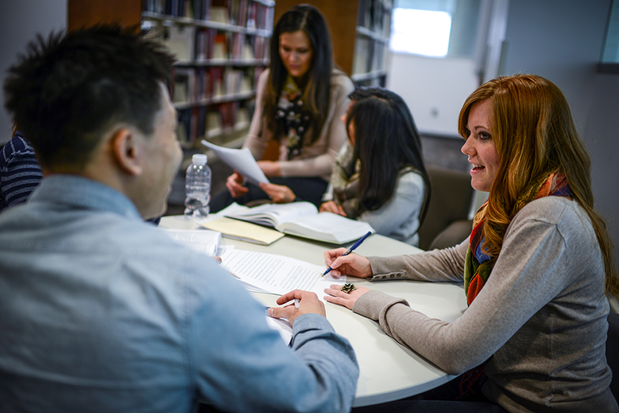 Students seated around a desk, having a discussion.