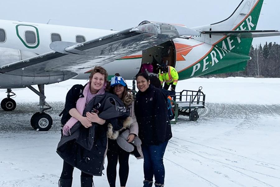 A group of people posing in front of a charter plane that just landed in Northern, MB.