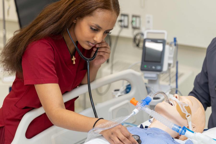 A respiratory therapy student works with a simulation patiet.