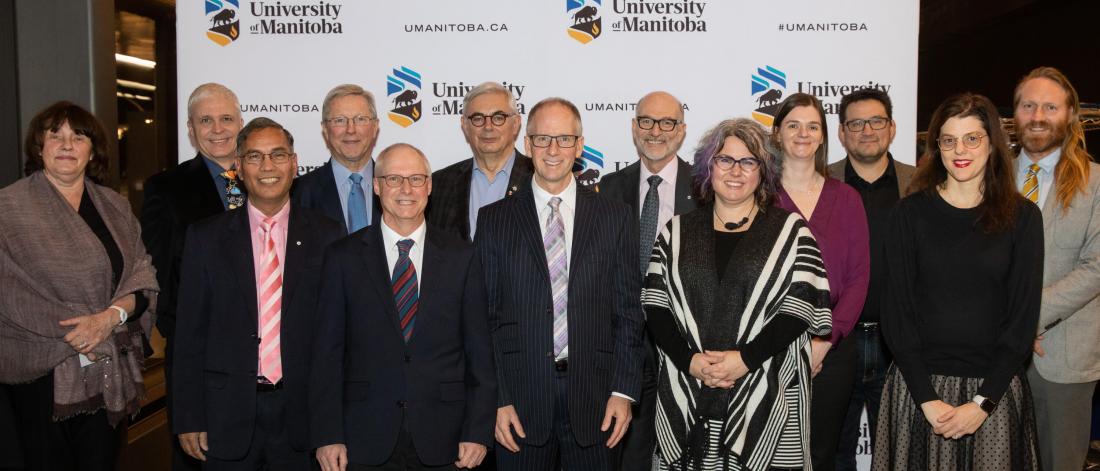 A group of 13 people stand together side by side to pose for a group photo at the December 2019 Research and Scholarly Excellence Celebration.