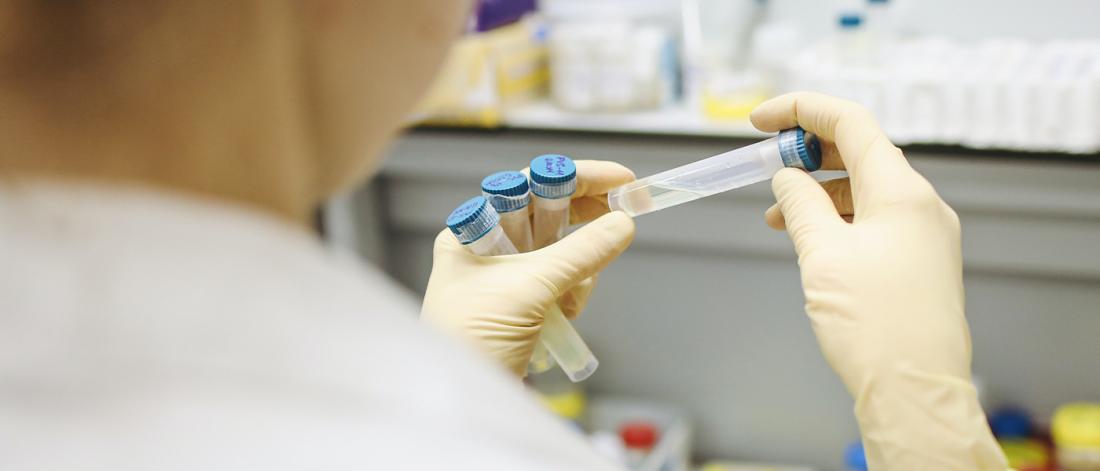 A researcher looking at a test tube very closely.