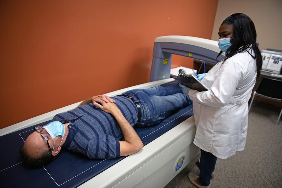 A volunteer lies on the DEXA machine while a technician takes a reading.