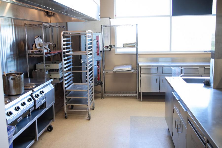 A commercial kitchen space with stove, ovens and countertops.
