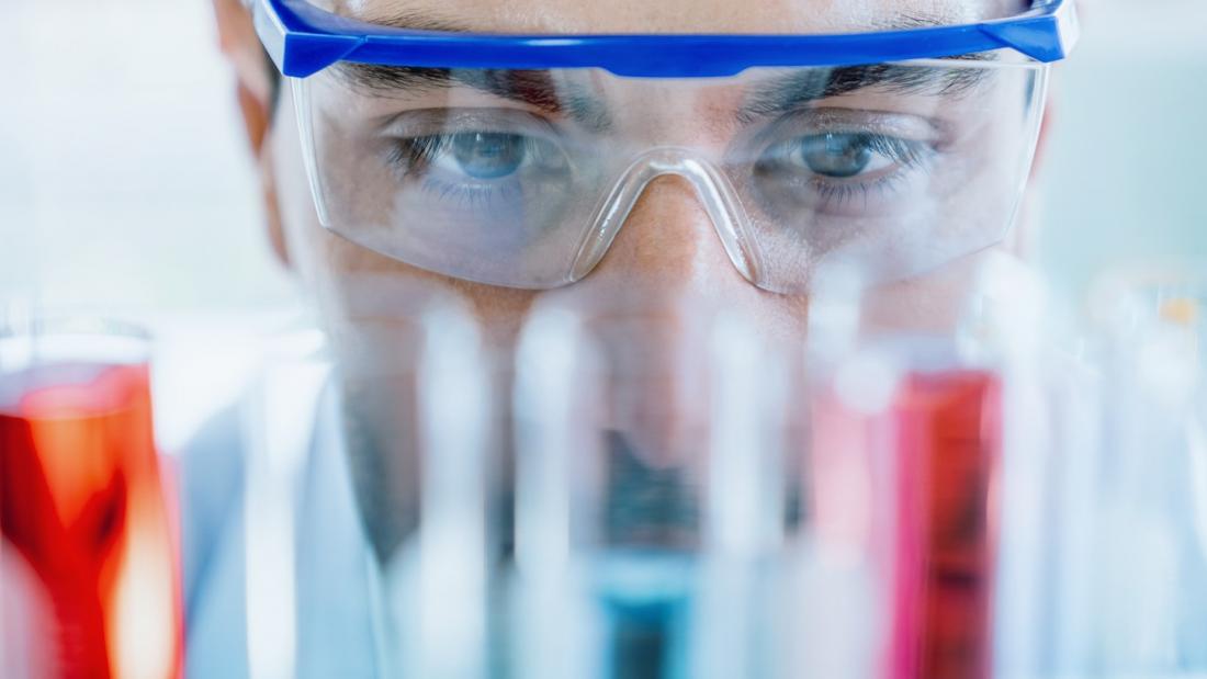 Student with protective glasses looking at chemistry vials.