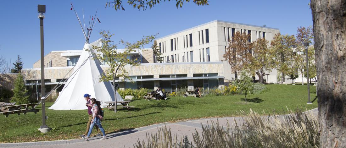a tipi beside a building with two persons walking
