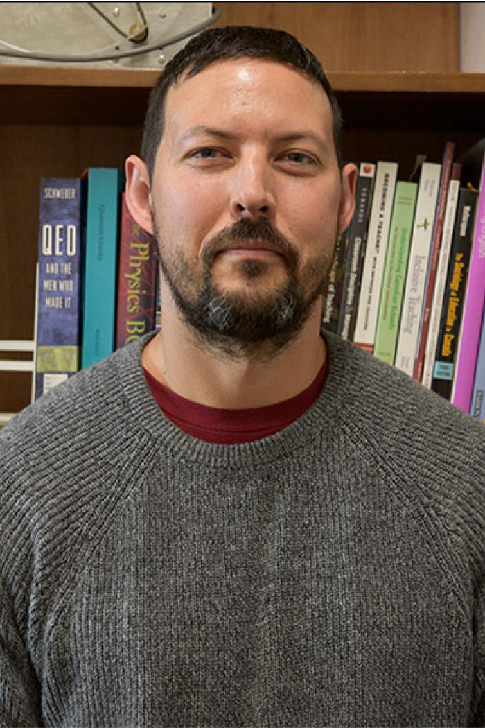Kyle Shiells wearing a gray sweater and smiling at the camera.