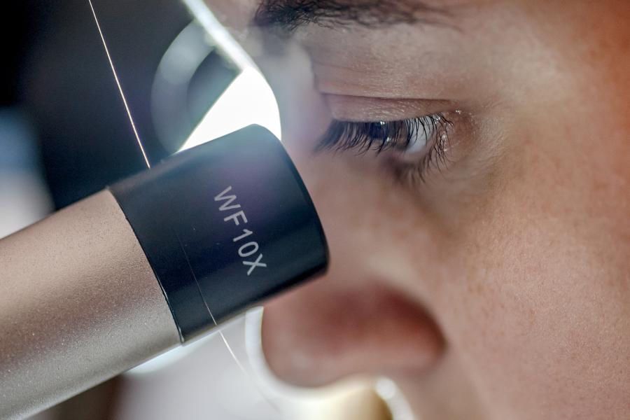 Close up of student looking through microscope