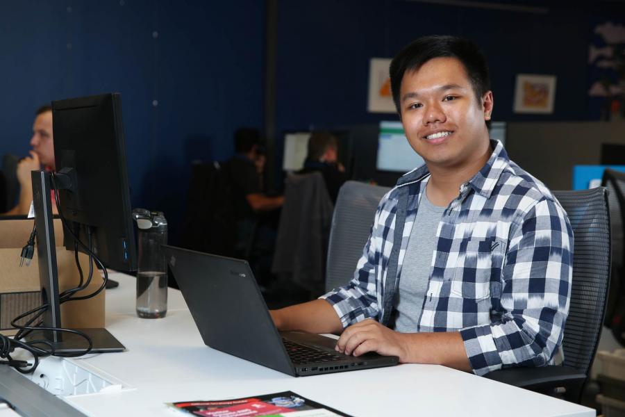 Andy Lun sitting behind a desk, working on a laptop.