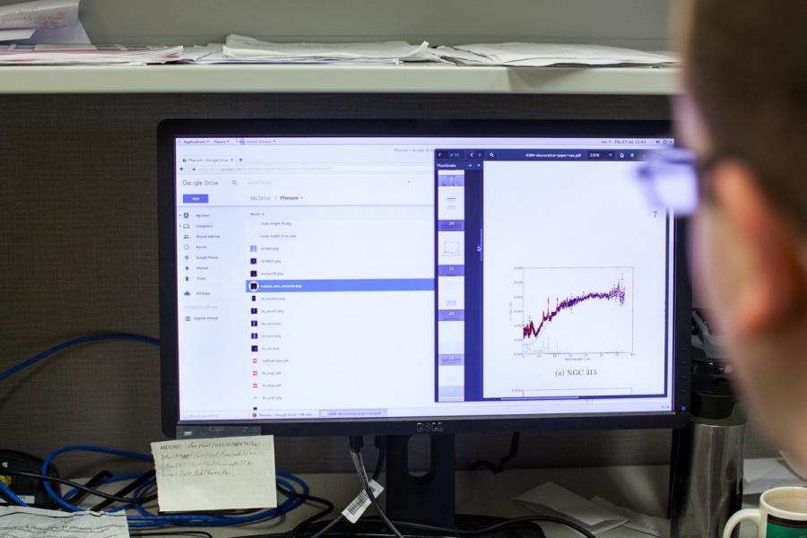 Dr ODea behind the computer screen doing Data Science research in Physics and Astronomy.