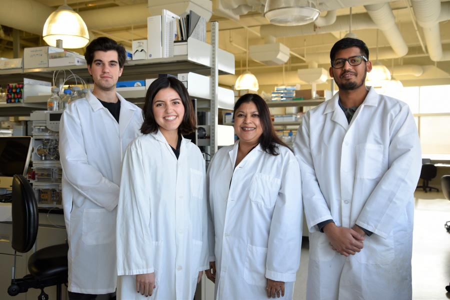 four people waring a laboratory coat smiling in front of the camera