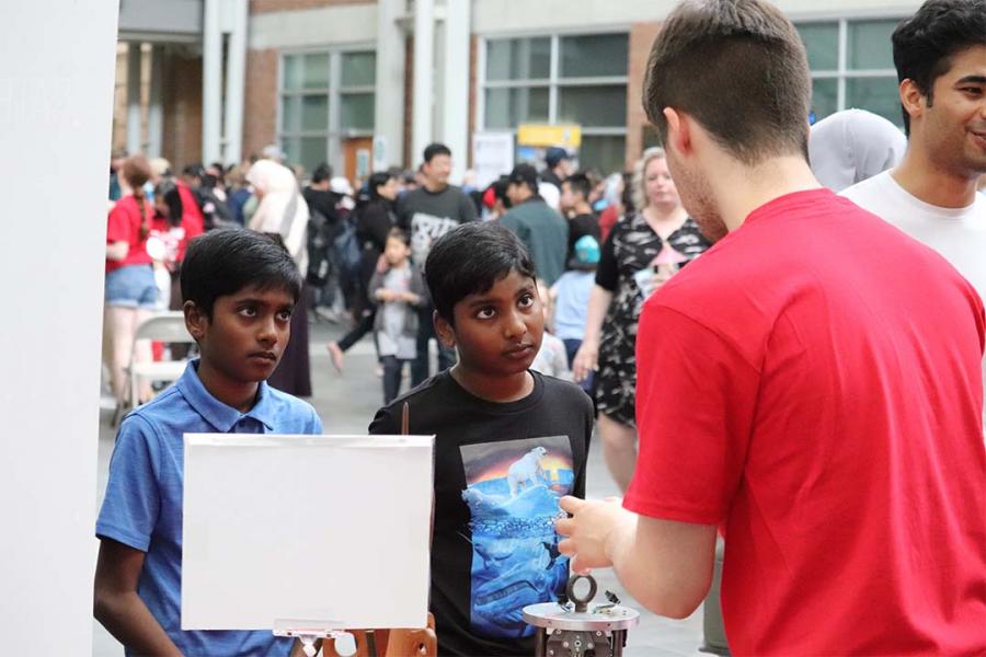 Two kids looking at a volunteer explaining a topic.