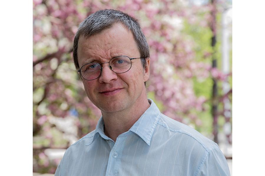 Georg Schreckenbach smiling at the camera in front of a pink tree.