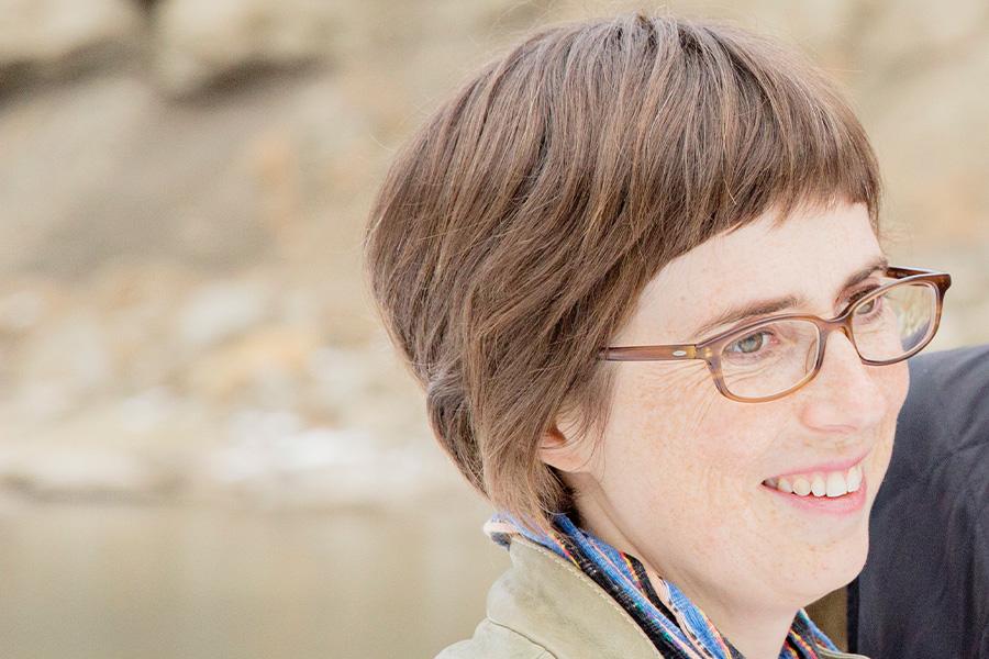 Olivia Wilkins wearing an eyeglass and smiling.