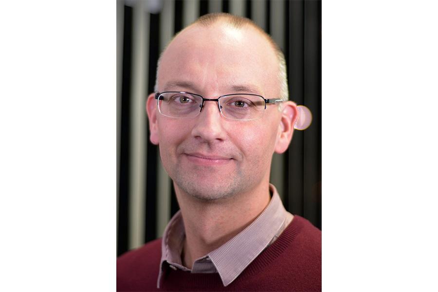 Andrew Goerzen wearing an eyeglass and smiling at the camera.