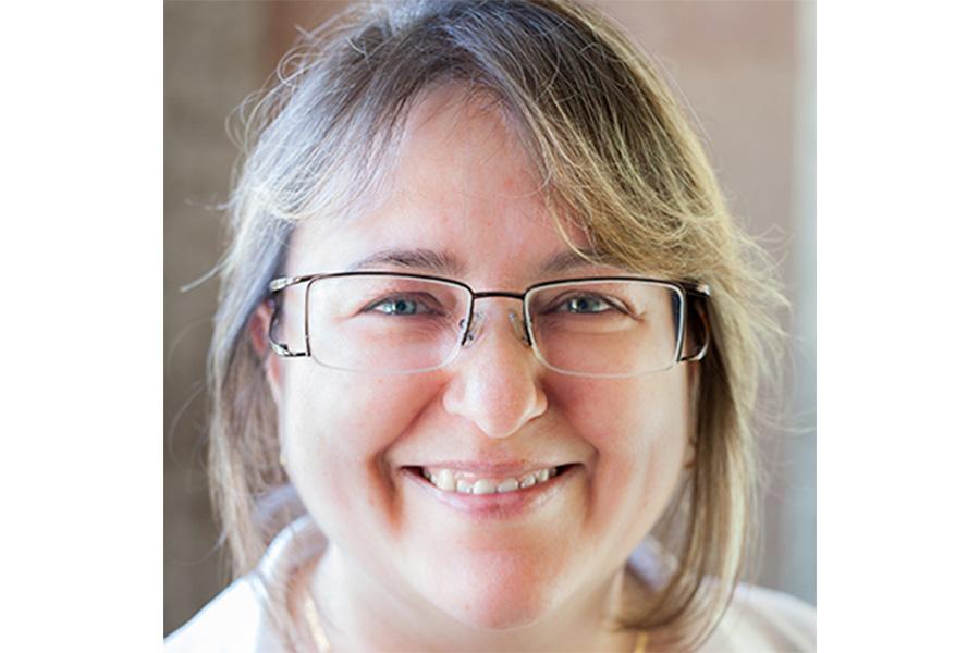 Karen Brassinga wearing an eyeglass and smiling at the camera.