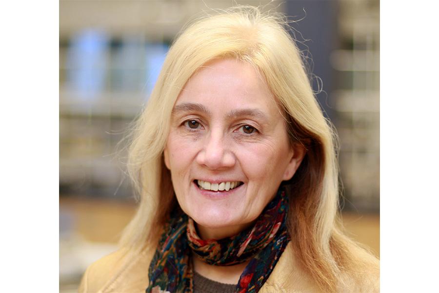 Kathleen Gough wearing a scarf and smiling at the camera.