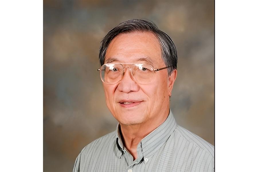 James Fu wearing a gray button down shirt and eyeglass smiling at the camera.